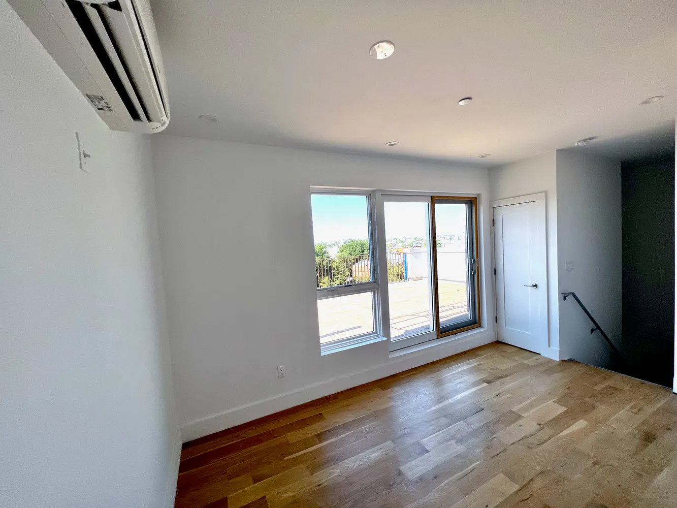 a view of an empty room with a window and wooden floor
