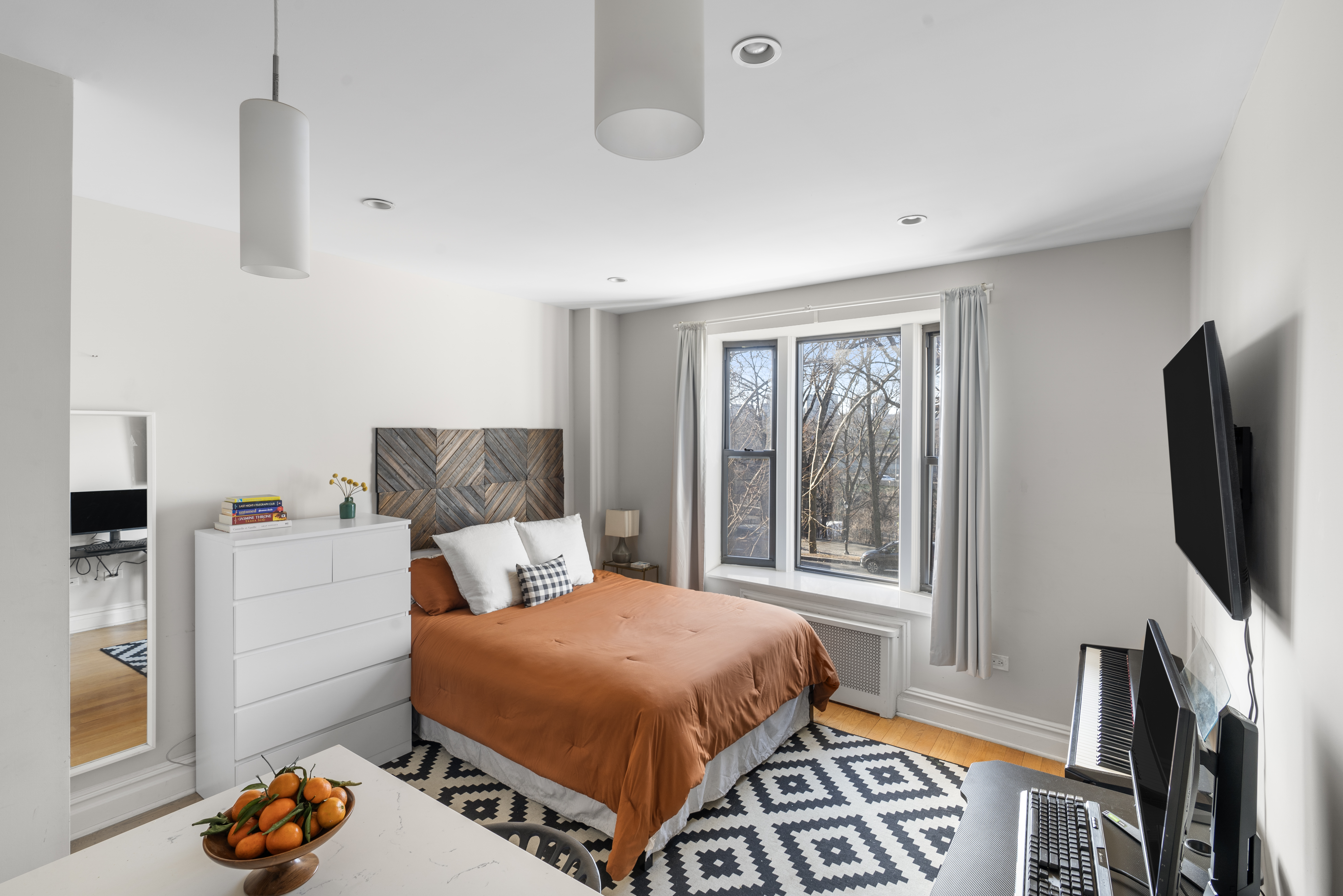 a bedroom with a bed and a flat tv screen on the dresser