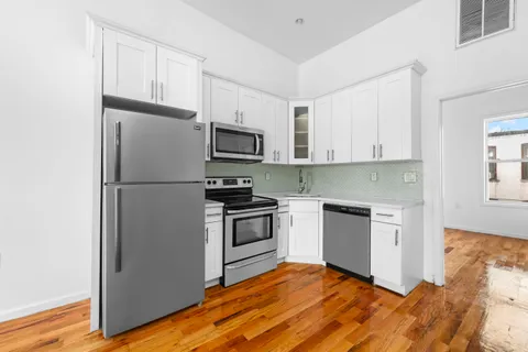 a kitchen with a refrigerator cabinets and wooden floor