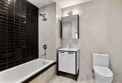 a bathroom with a granite countertop bathtub sink toilet and mirror