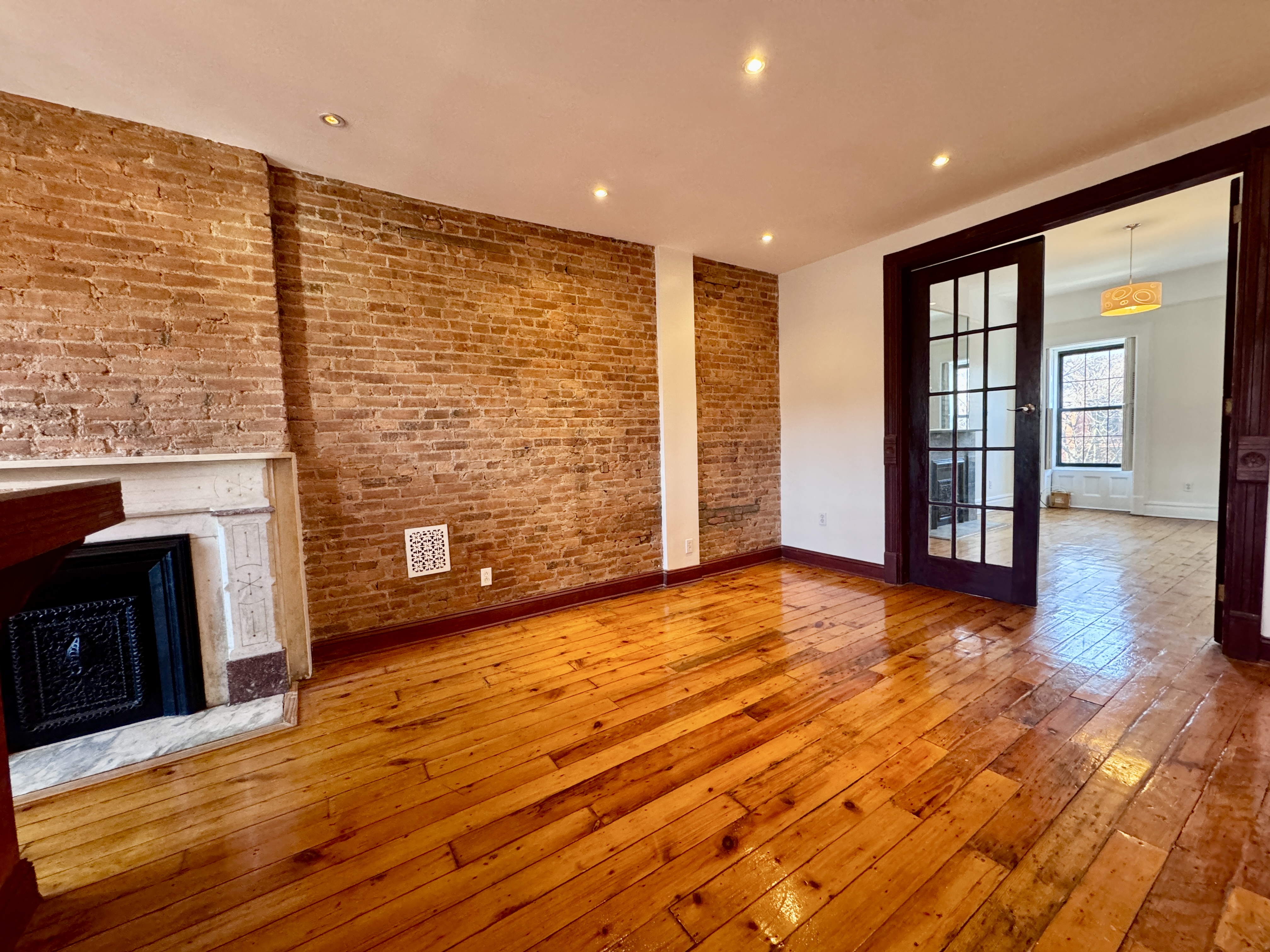 15 Arlington Place, Unit 3 Brooklyn, NY 11216 - Photo 7 of 14 a view of an empty room with a fireplace and wooden floor
