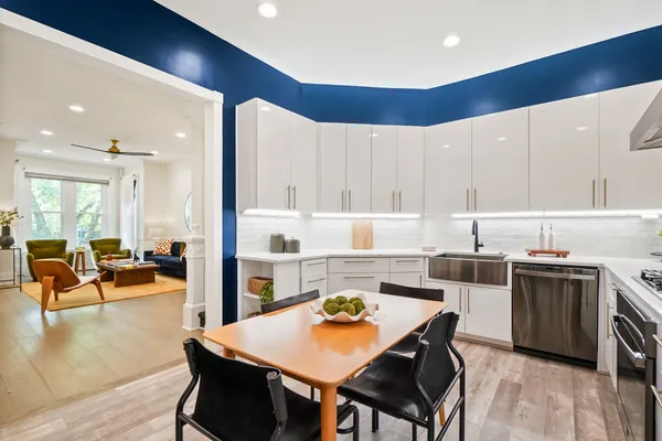 a kitchen with stainless steel appliances granite countertop a stove top oven a sink a dining table and chairs with wooden floor