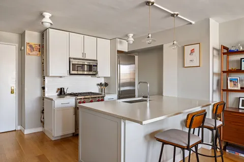 a kitchen with stainless steel appliances granite countertop a stove a sink dishwasher a refrigerator with a dining table and chairs