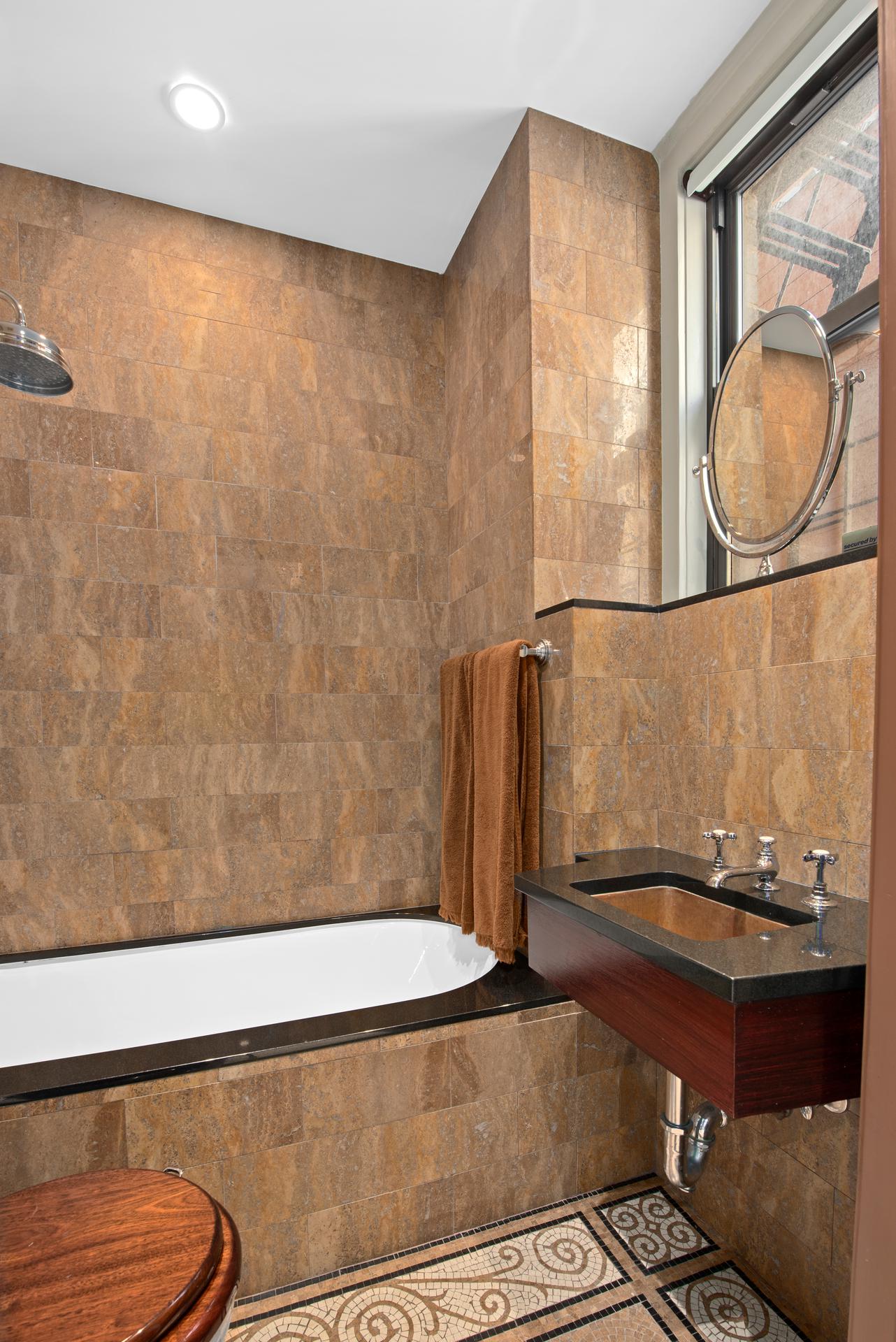 1140 5th Avenue, Unit 8C Manhattan, NY 10128 - Photo 13 of 16 a bathroom with a sink a mirror and a shower