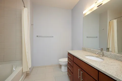 a bathroom with a granite countertop sink a toilet and a bathtub