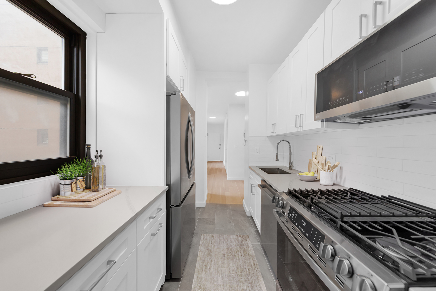 58 West 58th Street, Unit 21C Manhattan, NY 10019 - Photo 4 of 12 a kitchen with stainless steel appliances a sink stove and cabinets