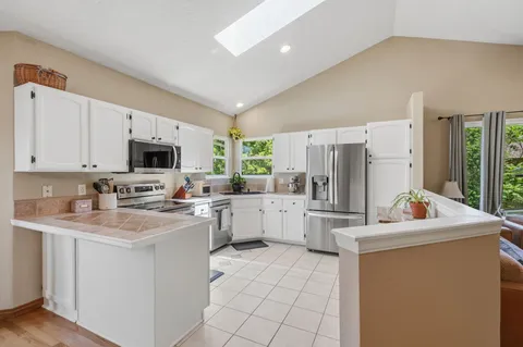 a kitchen with white cabinets stainless steel appliances and a window
