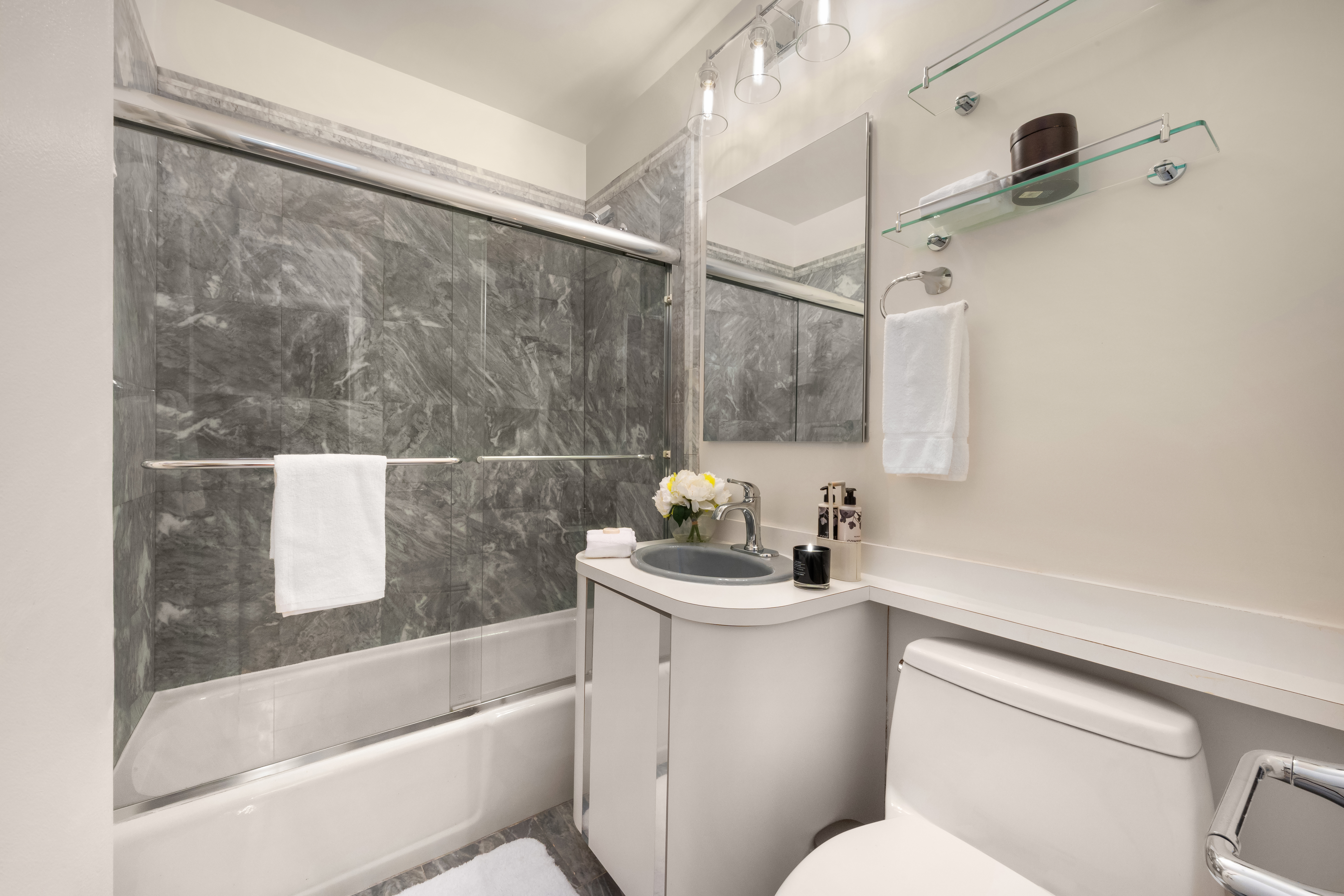 400 East 56th Street, Unit 38S Manhattan, NY 10022 - Photo 11 of 16 a bathroom with a sink a toilet and shower