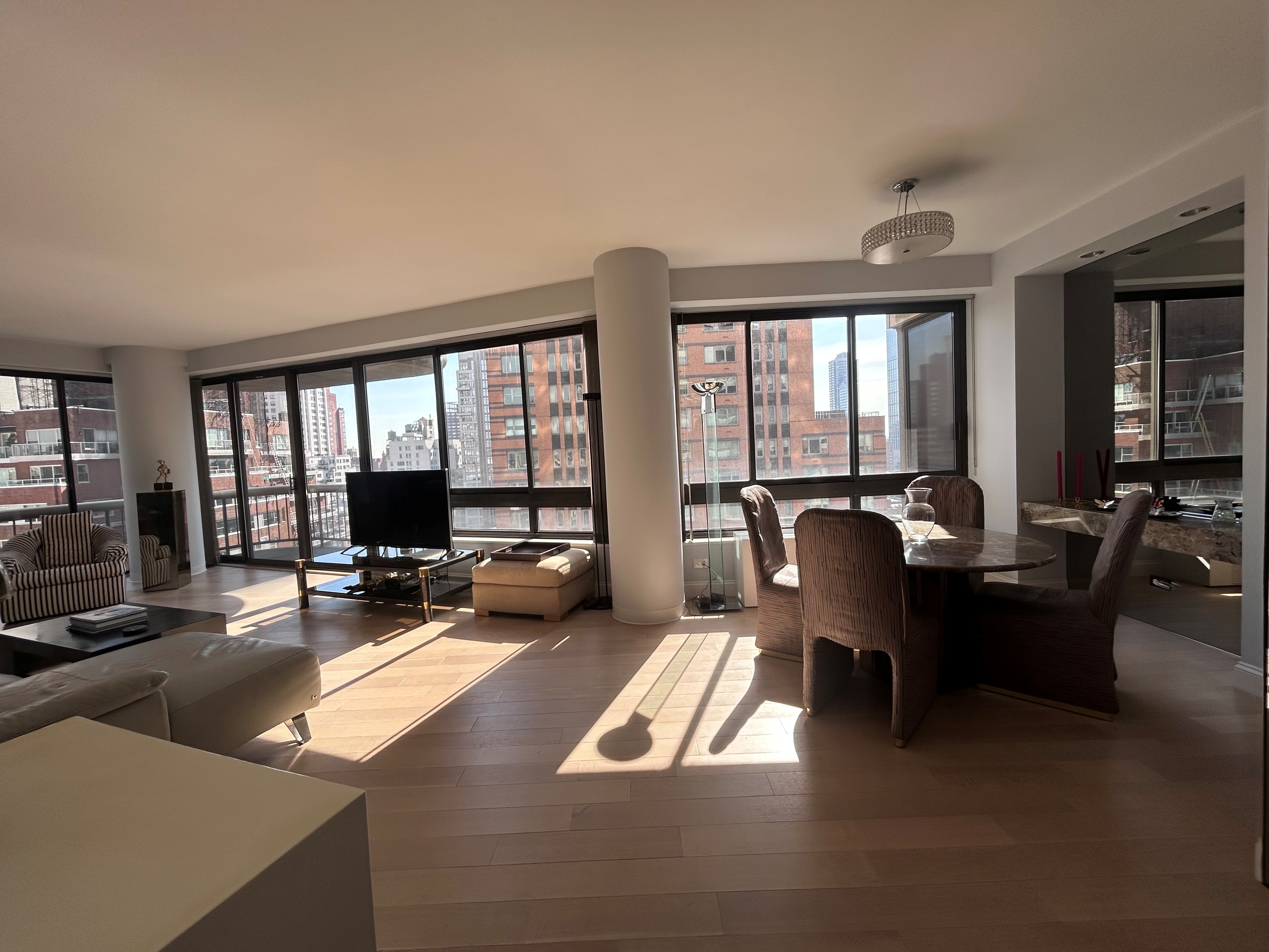 167 East 61st Street, Unit 20E Manhattan, NY 10065 - Photo 6 of 24 a living room with furniture floor to ceiling windows and a dining table