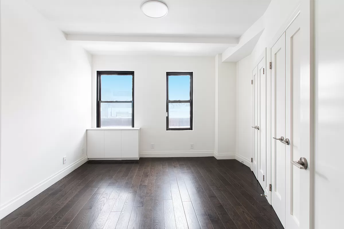 230 Riverside Drive, Unit 17D Manhattan, NY 10025 - Photo 6 of 18 an empty room with wooden floor and windows