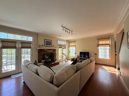 a living room with furniture large window and wooden floor