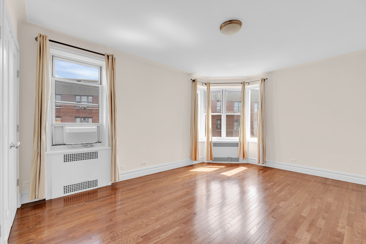 73-12 35th Avenue, Unit A62 Queens, NY 11372 - Photo 6 of 10 a view of an empty room with wooden floor and a window