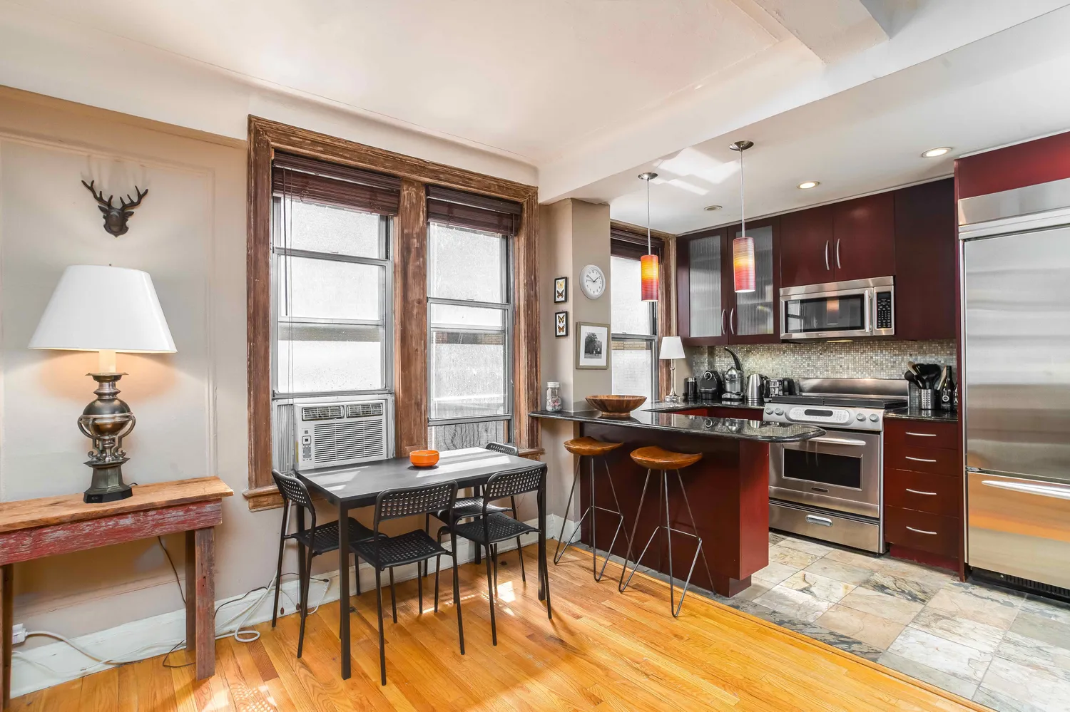 a open kitchen with stainless steel appliances granite countertop a stove top oven a sink dishwasher a dining table and chairs with wooden floor