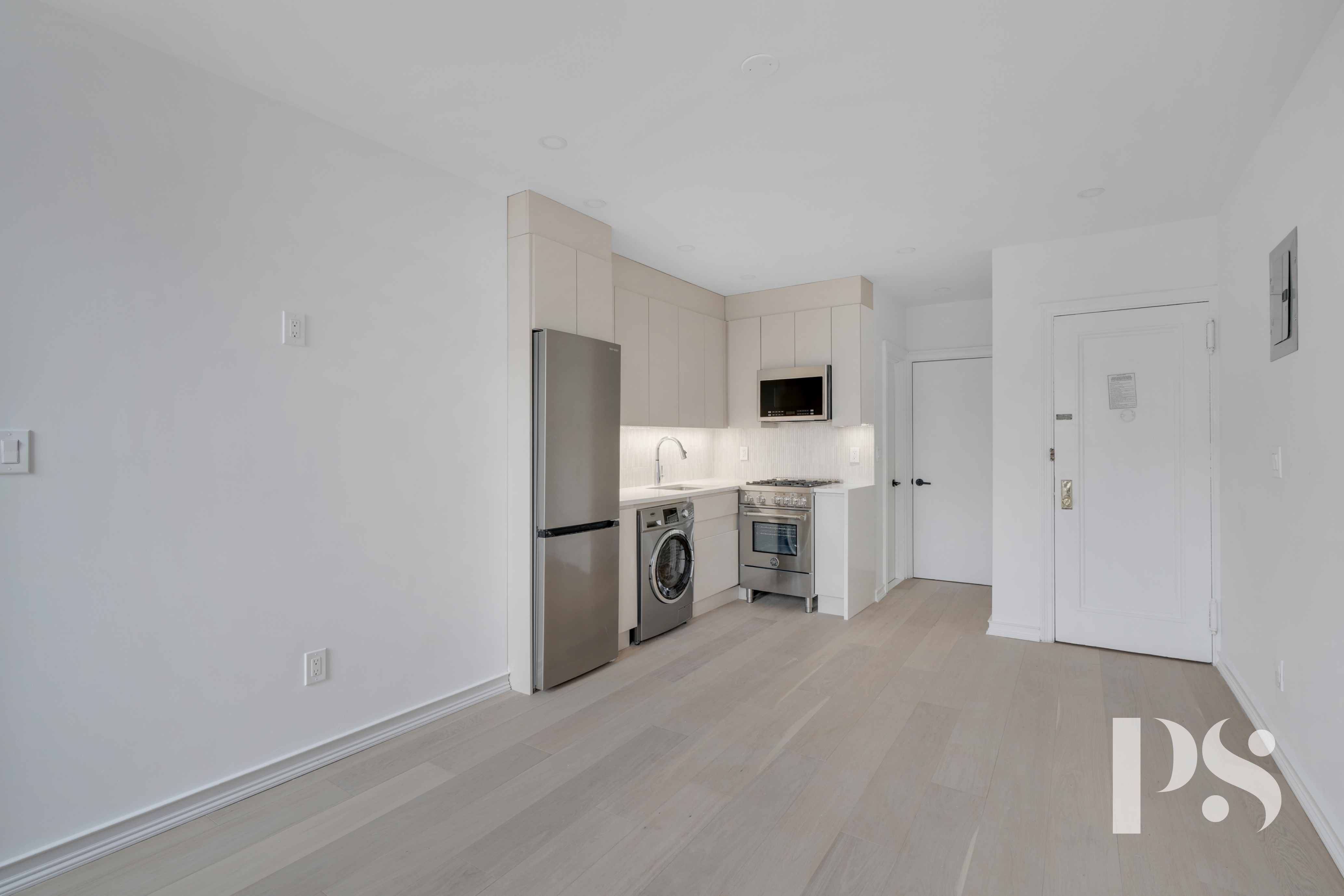 51 Jane Street, Unit 16 Manhattan, NY 10014 - Photo 2 of 6 a view of a kitchen with refrigerator and white cabinets