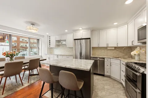 a kitchen with kitchen island granite countertop a stove a sink a refrigerator dining table and chairs