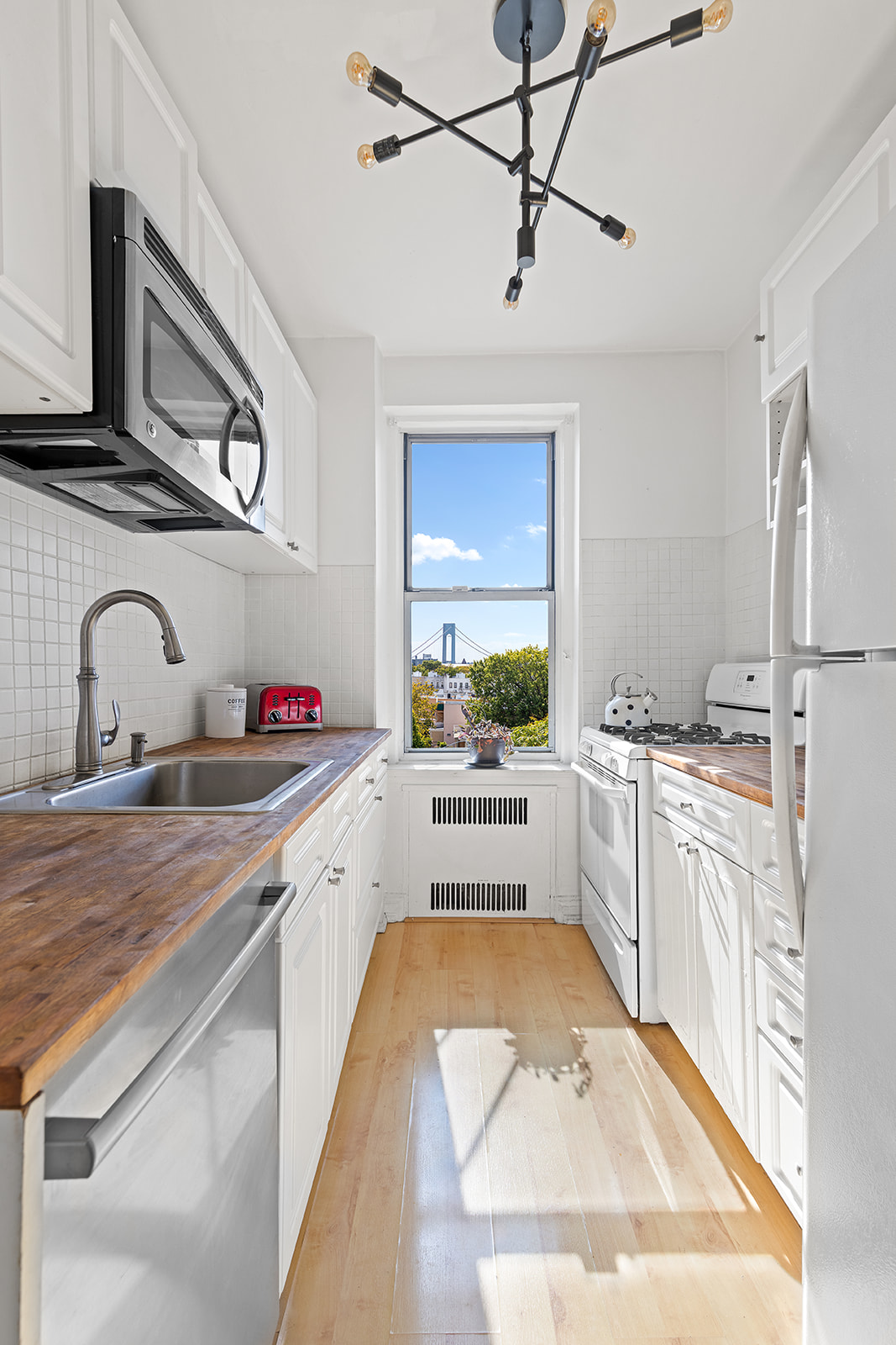 601 79th Street, Unit E12 Brooklyn, NY 11209 - Photo 3 of 8 a large white kitchen with stainless steel appliances granite countertop a sink and cabinets