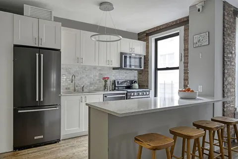 a kitchen with stainless steel appliances a refrigerator a stove a sink and white cabinets