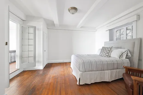 a bedroom with a bed and wooden floor