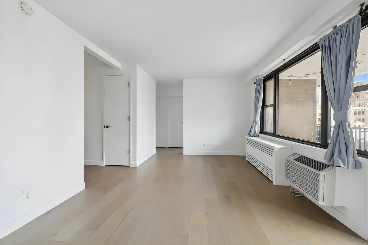 an empty room with wooden floor and mirror