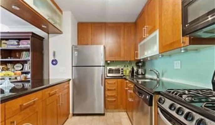 510 East 80th Street, Unit 4D Manhattan, NY 10075 - Photo 16 of 20 a kitchen with stainless steel appliances granite countertop a refrigerator and a stove