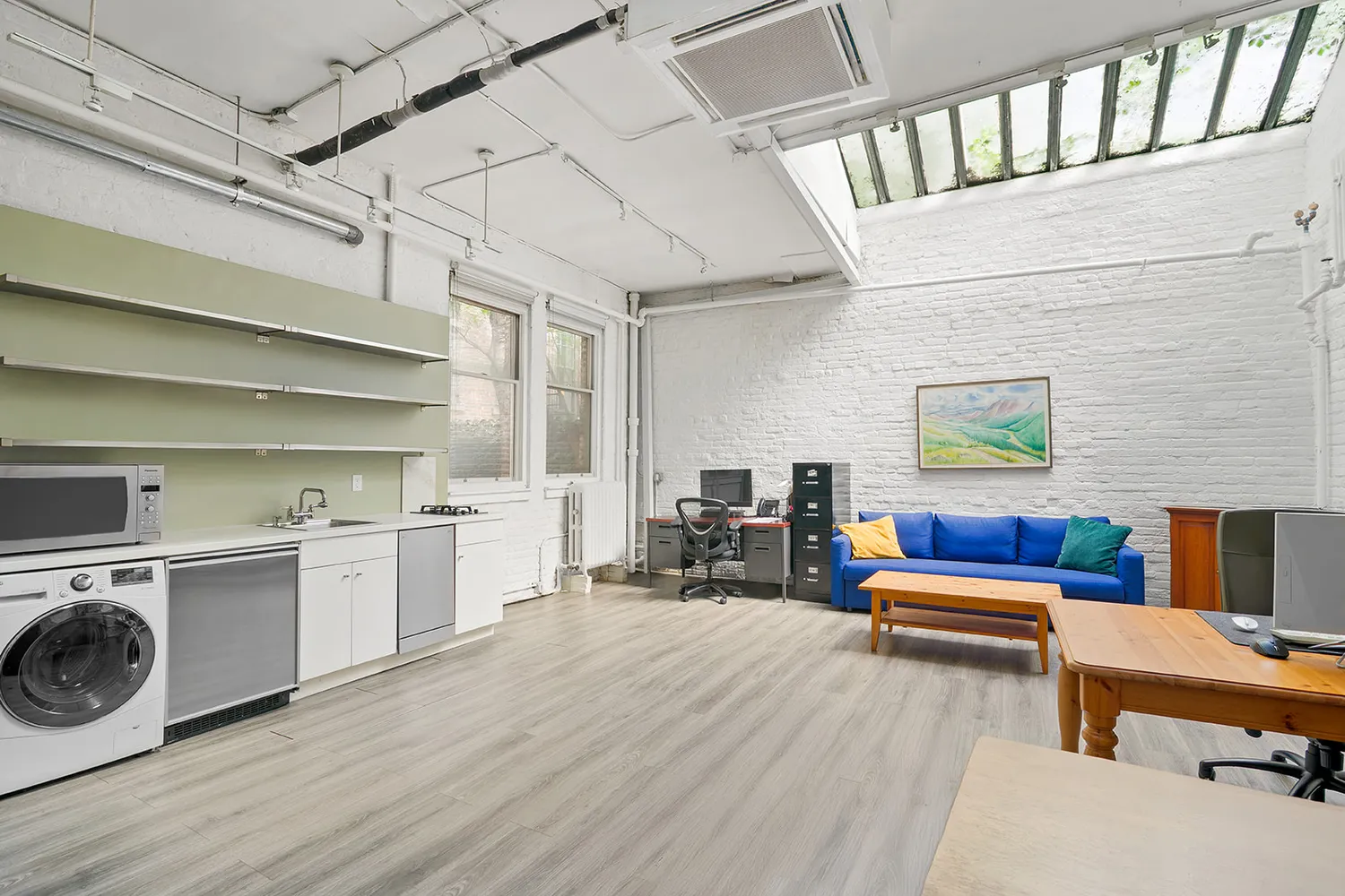 a view of living room kitchen with stainless steel appliances wooden floor and furniture