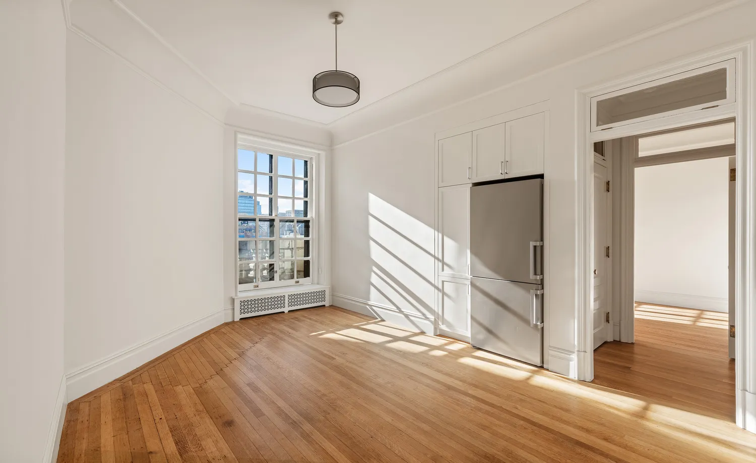 a view of an empty room with wooden floor and a window