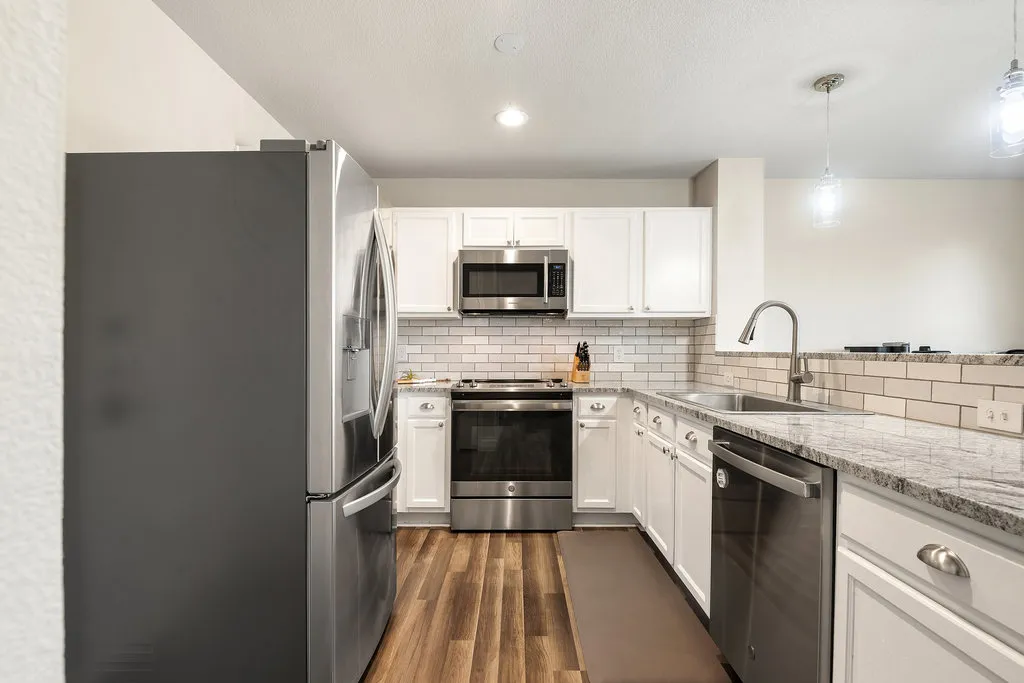 a kitchen with stainless steel appliances a sink a stove a microwave cabinets and a counter top