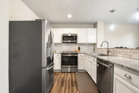 a kitchen with stainless steel appliances a sink a stove a microwave cabinets and a counter top