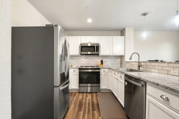 a kitchen with stainless steel appliances a sink a stove a microwave cabinets and a counter top