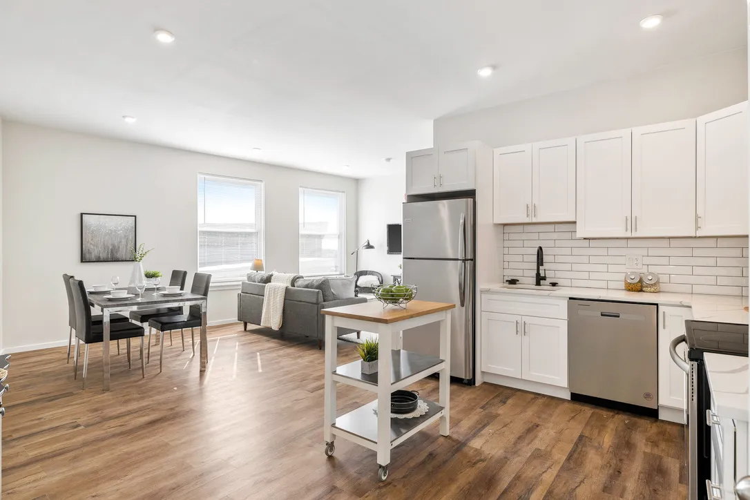 a kitchen with stainless steel appliances granite countertop a sink stove refrigerator and white cabinets with wooden floor