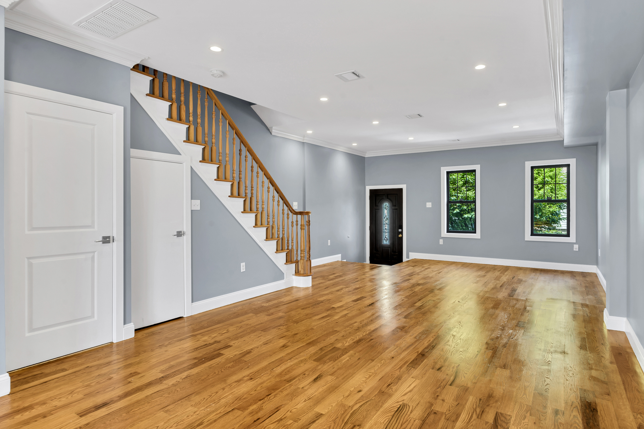 a view of an empty room with wooden floor and stairs