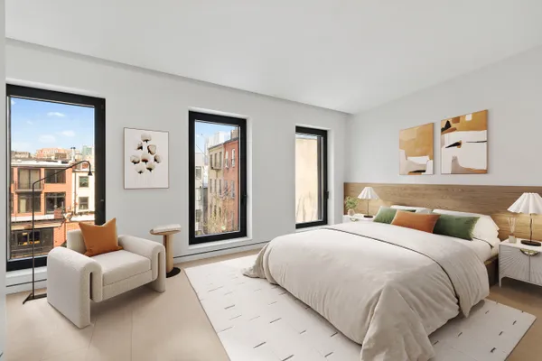 a bedroom with a large bed couch and windows