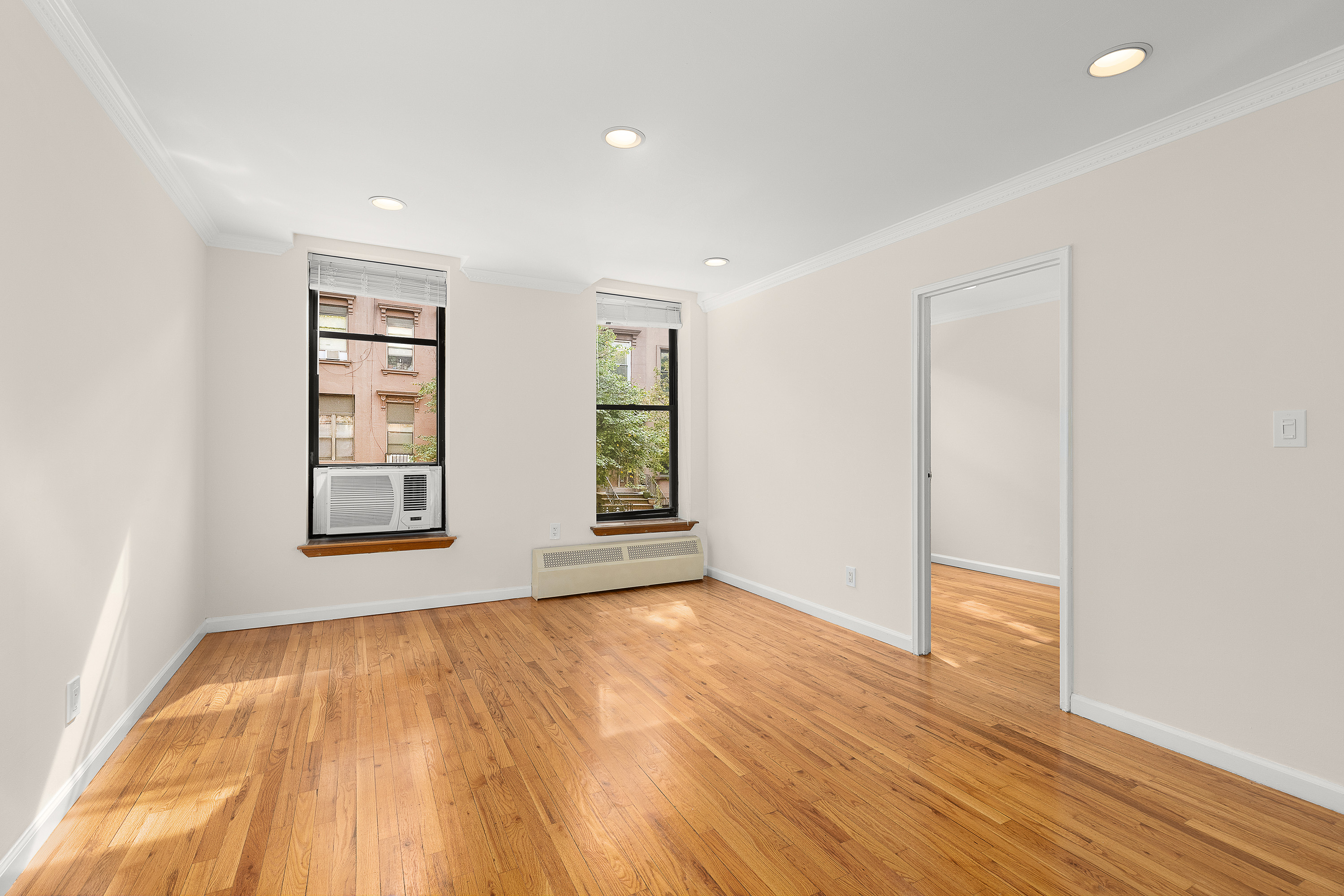 an empty room with wooden floor and windows