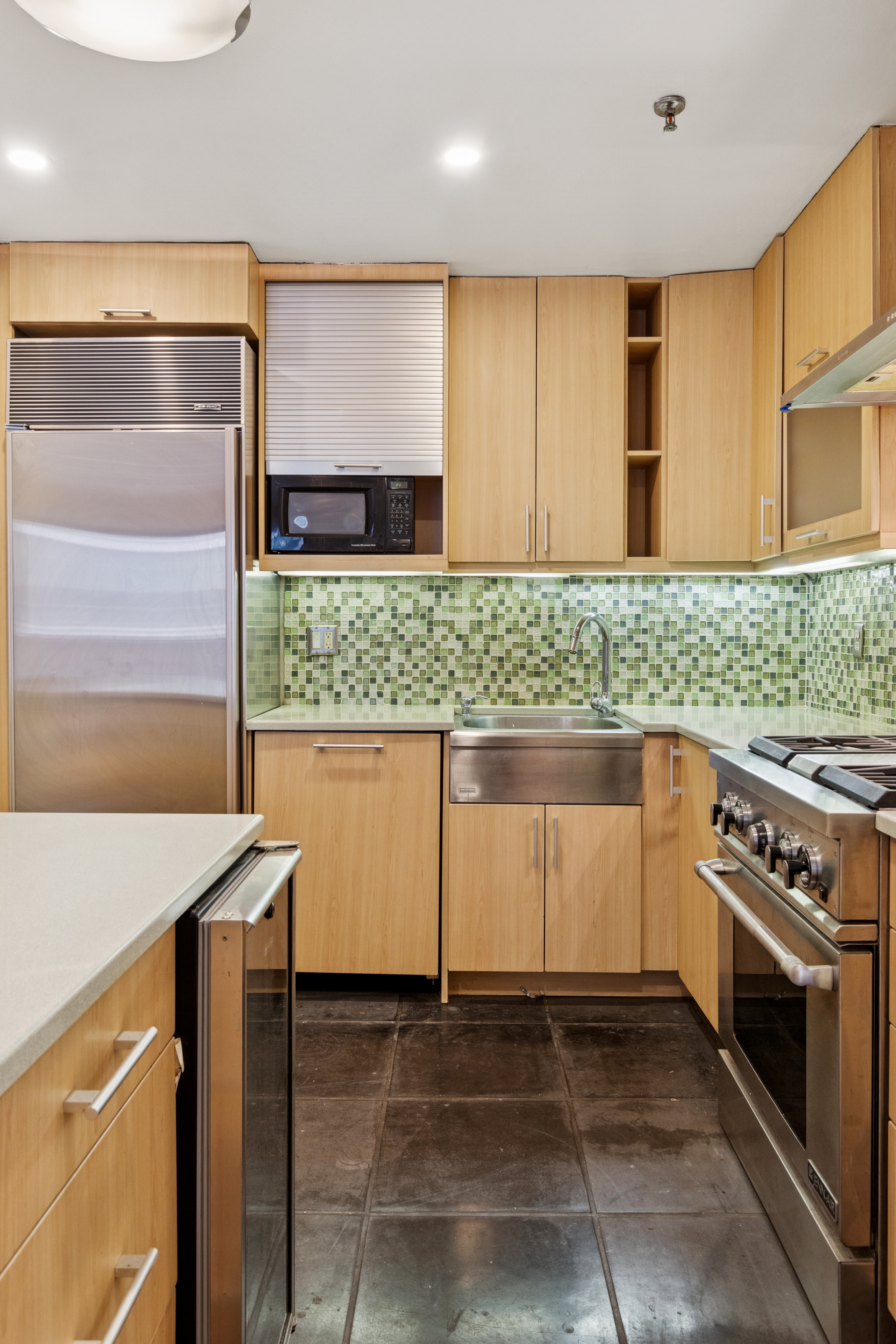 136-140 West 23rd Street, Unit 4CC Manhattan, NY 10011 - Photo 6 of 13 a kitchen with stainless steel appliances kitchen island granite countertop a stove a sink and a microwave