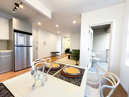 a room with furniture a flat screen tv and kitchen view