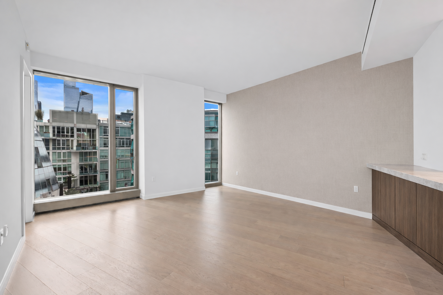 a view of an empty room with a window and wooden floor