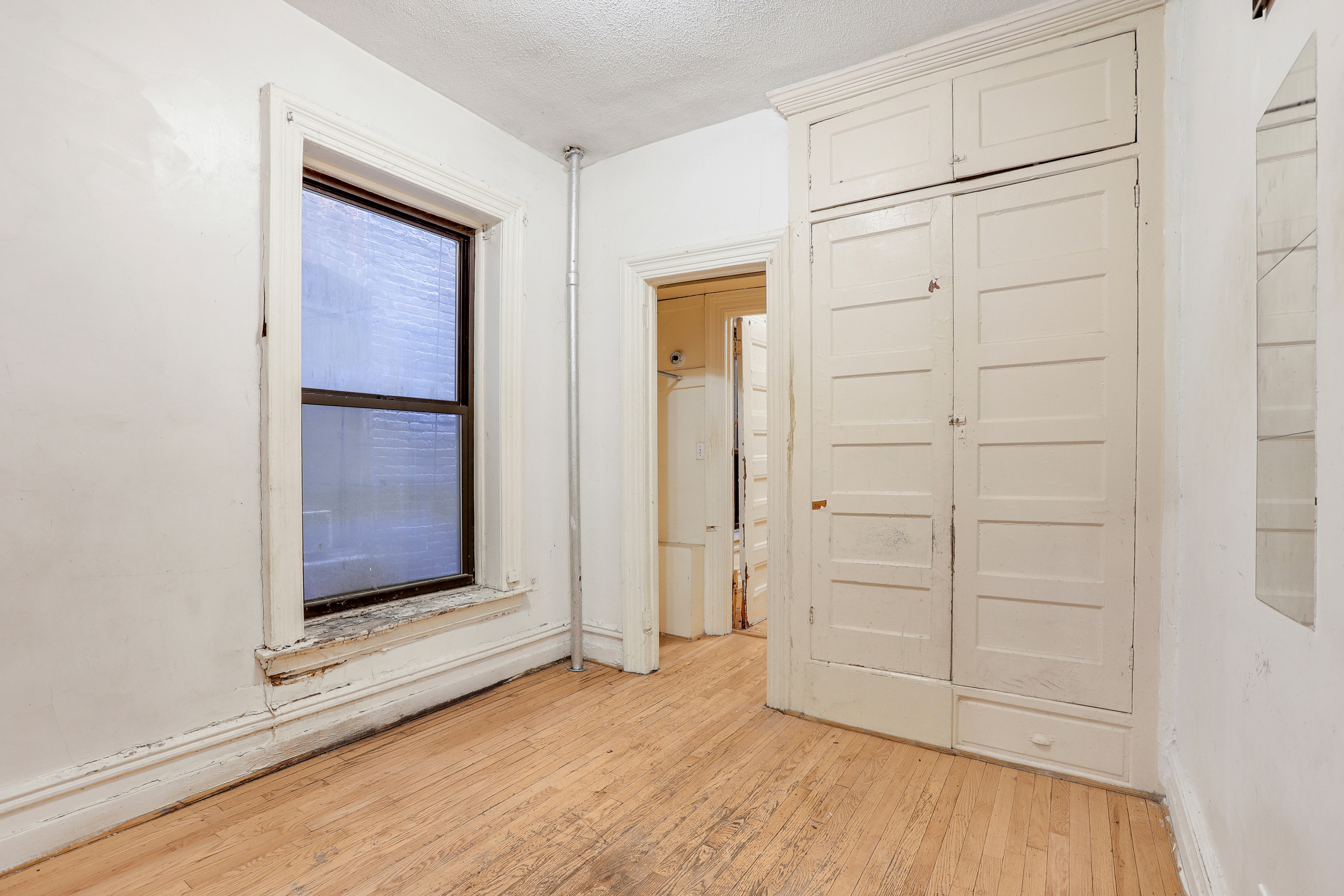 282 Manhattan Avenue, Unit 3N Manhattan, NY 10026 - Photo 14 of 17 an empty room with wooden floor closet and windows