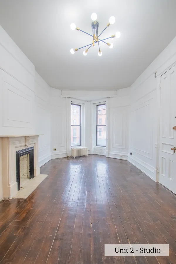 a view of an empty room with a window and wooden floor
