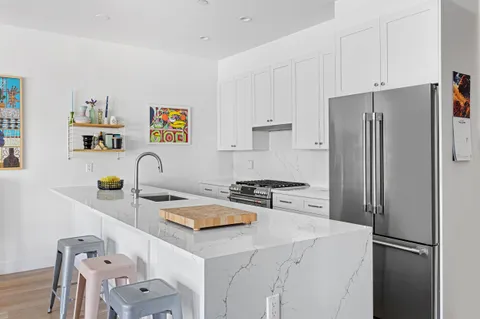 a kitchen with stainless steel appliances a refrigerator sink and white cabinets