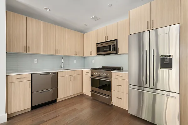 17 Convent Avenue, Unit 3D Manhattan, NY 10027 - Photo 4 of 9 a kitchen with stainless steel appliances white cabinets and a refrigerator