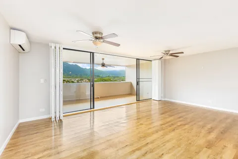 a view of empty room with wooden floor and fan