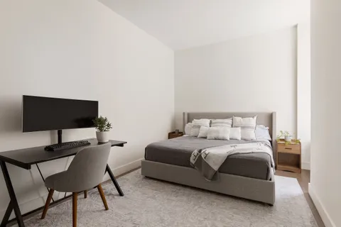 a bedroom with a bed a chair and a potted plant