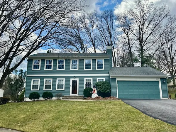 a front view of a house with a garden and trees