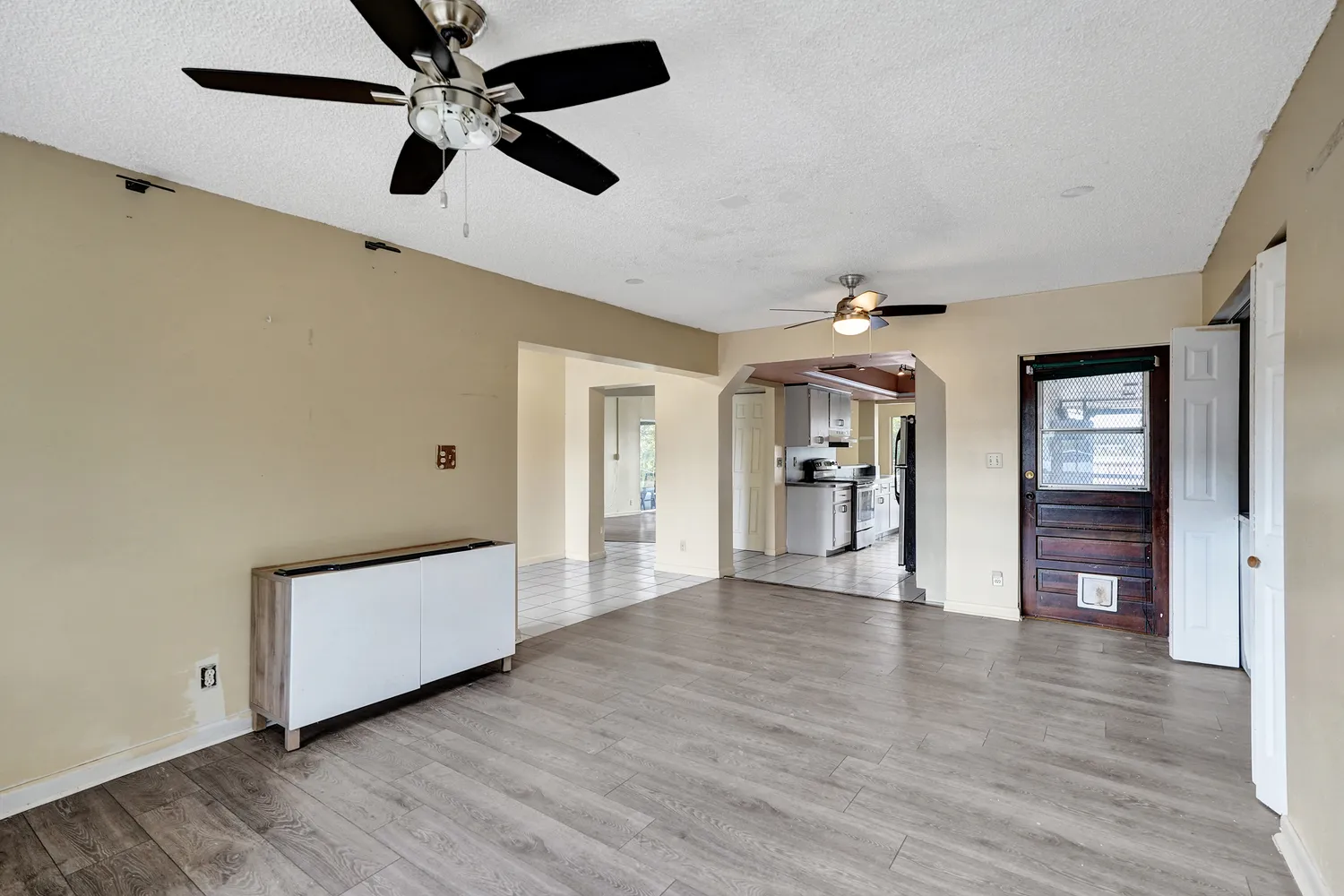 a view of an empty room with window and chandelier fan