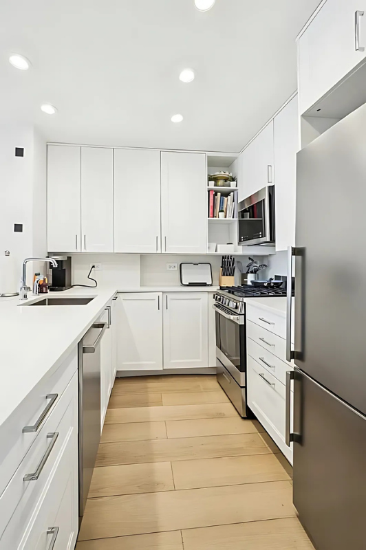 215 West 95th Street, Unit 9J Manhattan, NY 10025 - Photo 3 of 11 a kitchen with white cabinets stainless steel appliances and sink