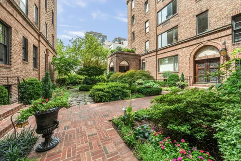 a front view of a multi story residential apartment building with yard and bench