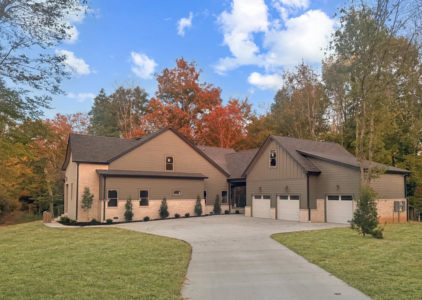 a view of a white house next to a yard with big trees and plants
