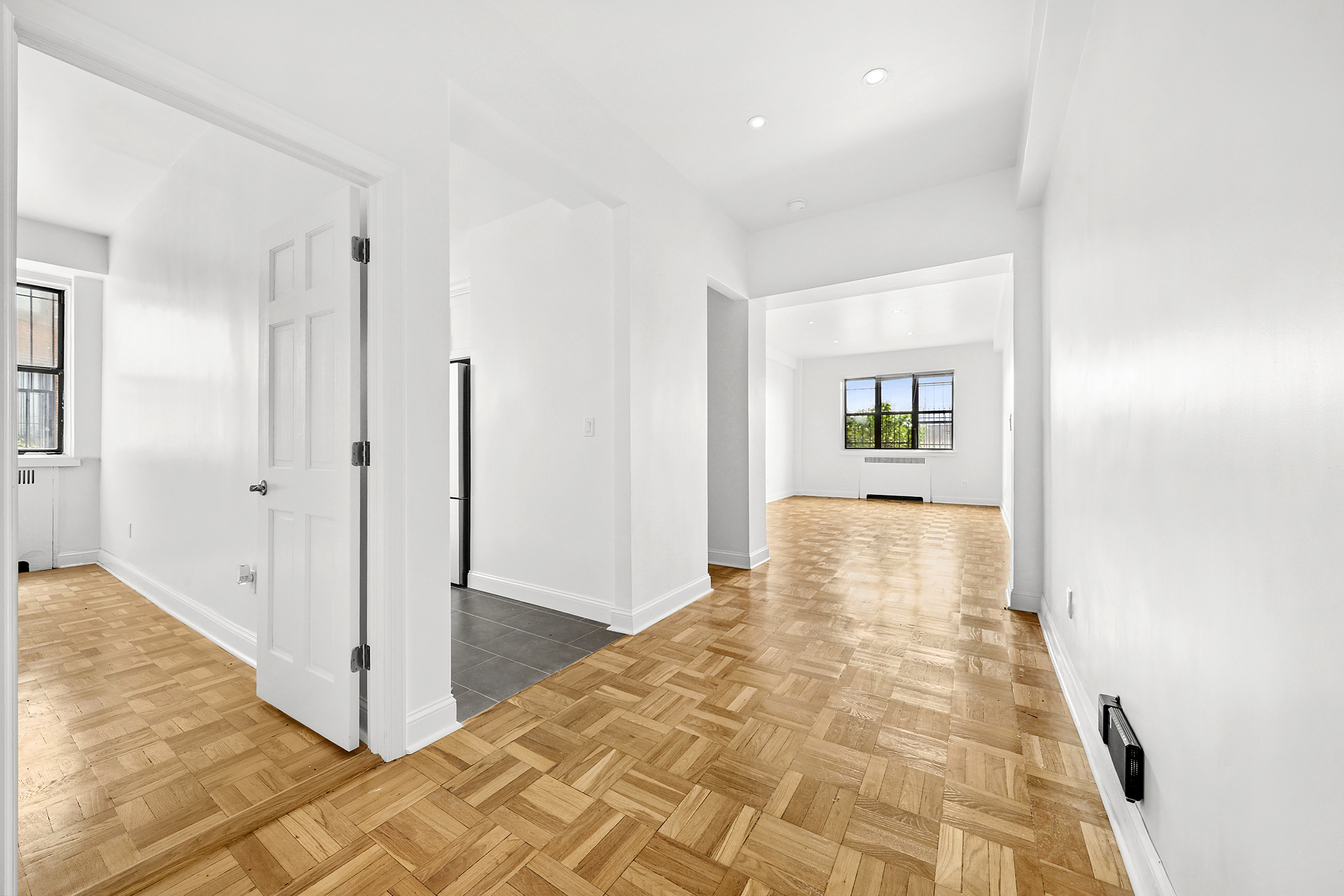 a view of a big room with wooden floor and windows
