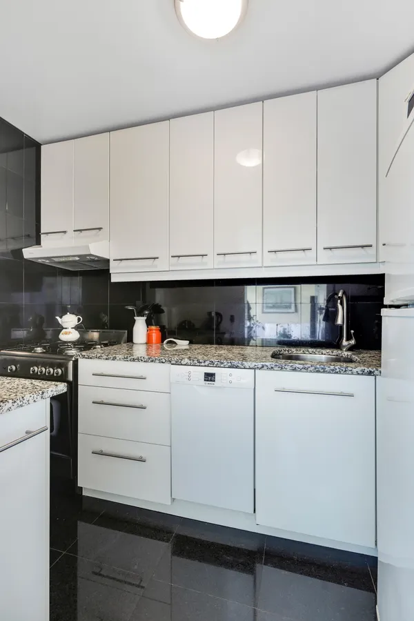 a kitchen with granite countertop white cabinets and white appliances