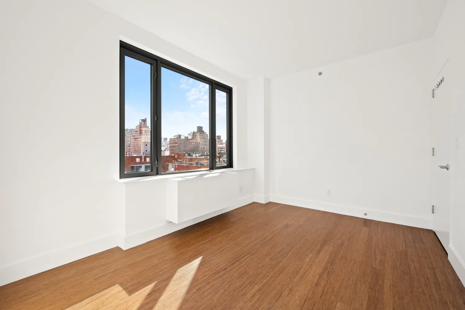 a view of an empty room with wooden floor and a window